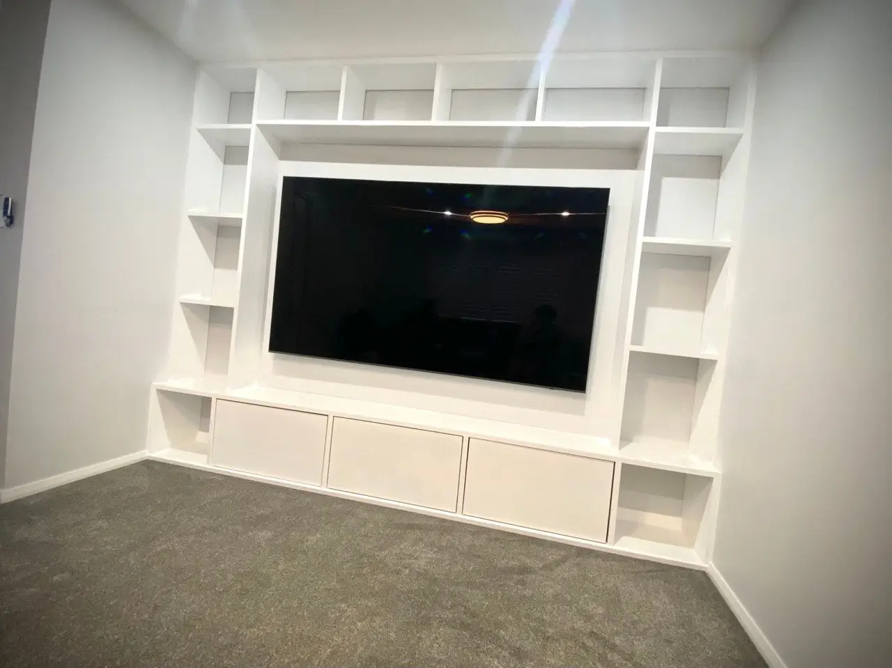 Custom built-in entertainment unit with shelving and cabinets, built by Trusted
